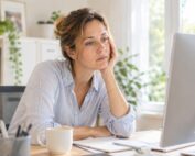 Müde Frau sitzt nachdenklich vor einem Computerbildschirm im Büro.